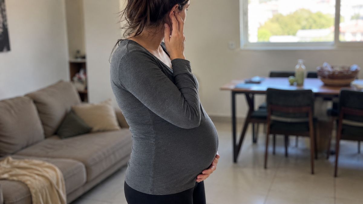 אישה בהריון נוגעת באוזנה בעקבות תחושת לחץ או אטימות